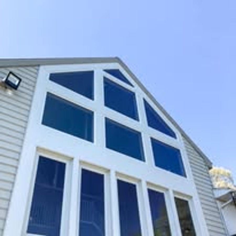 Gable window wall with new white trim against blue-gray siding