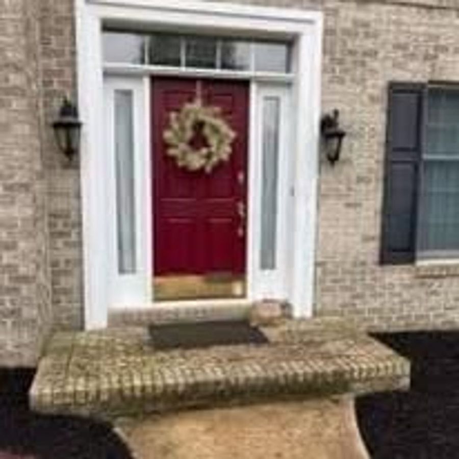 Brick home entry with a red front door, white trim, and new overhead flashing